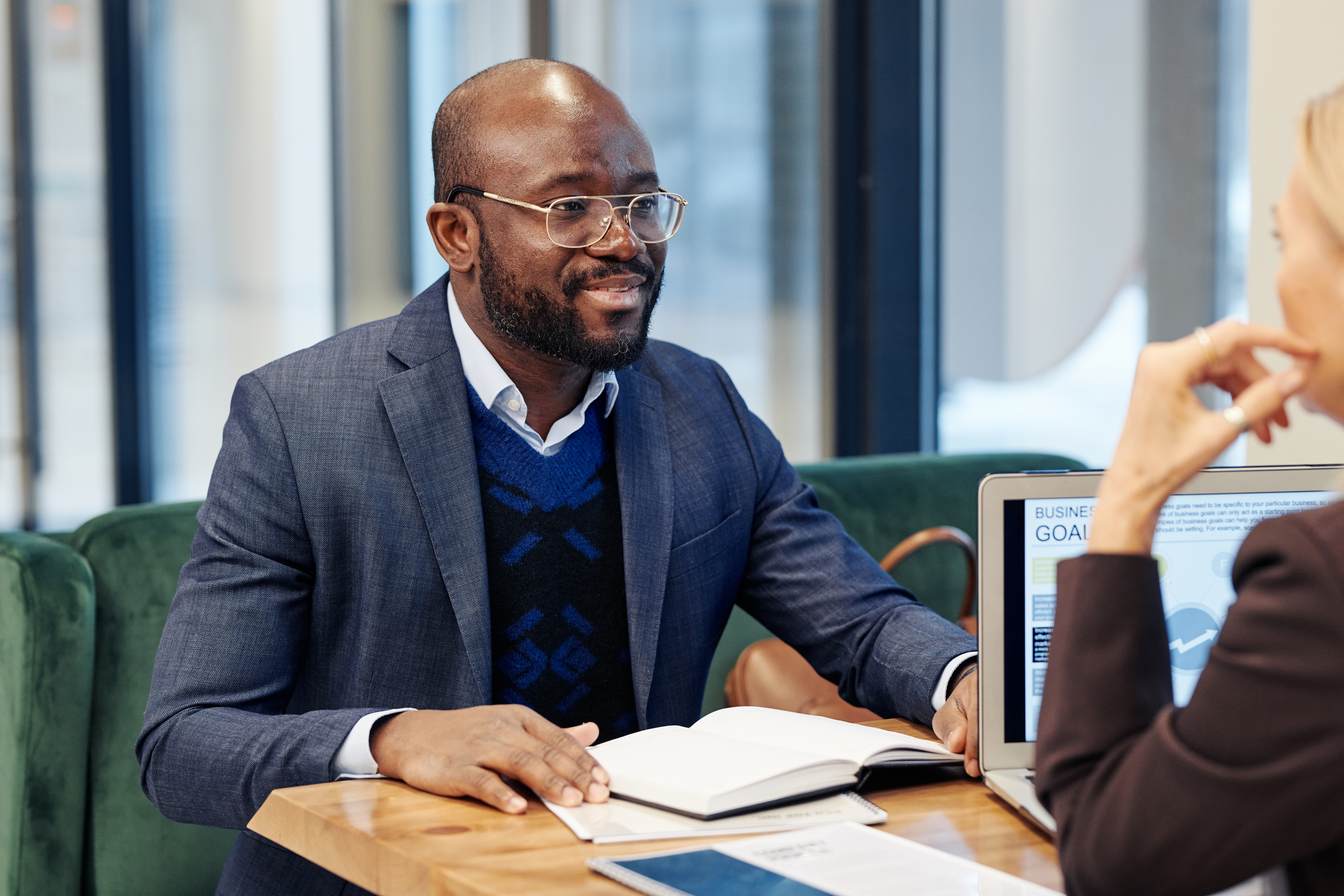 African successful lawyer listening to his client while they sitting at the table during business meeting